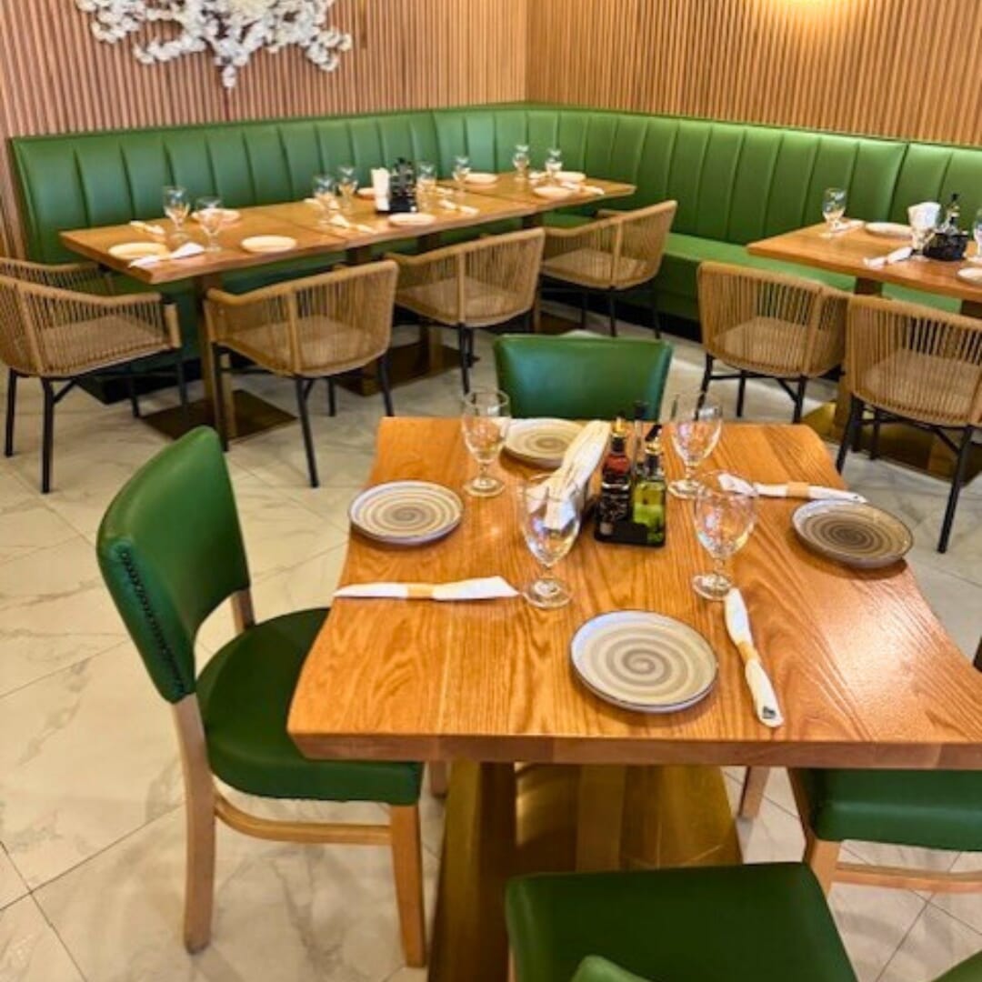 Bennett green restaurant chairs and rope armchairs surround red-oak tables on gold bases, showcasing cohesive commercial dining design.