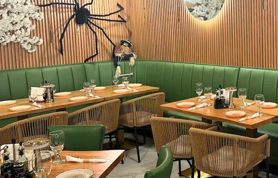 Interior of La Juliana Miami featuring indoor and outdoor rattan chairs, rustic plank tables and gold bases